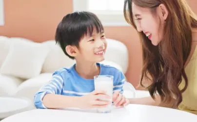 笑顔で牛乳コップ持った子供と女性